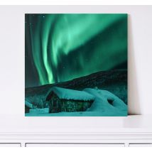 Tableau avec des aurores boréales au-dessus d'un chalet enneigé